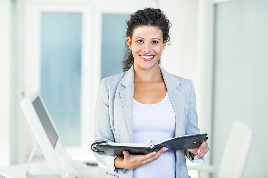 Portrait of smiling beautiful businesswoman holding document in office