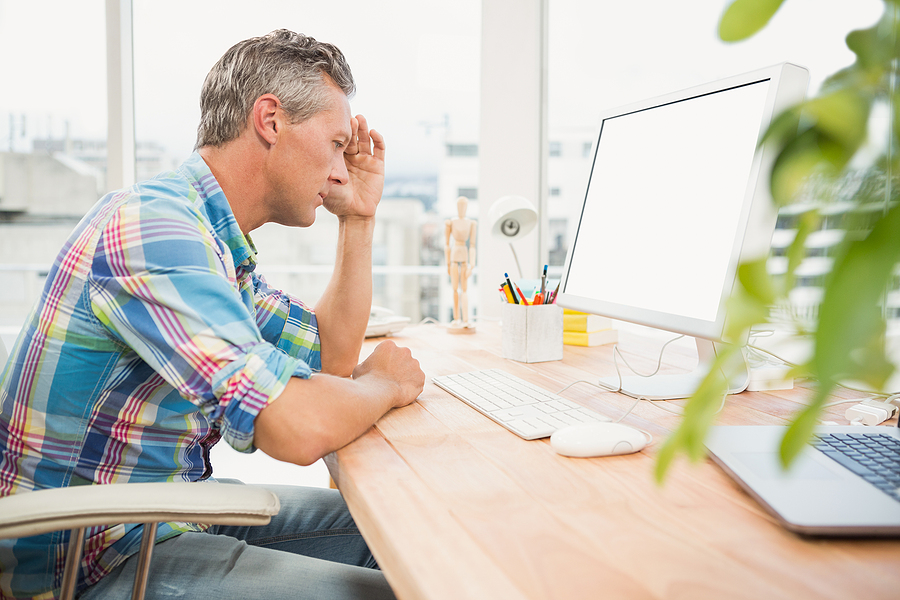 man sitting frustrated at desk in front of computer