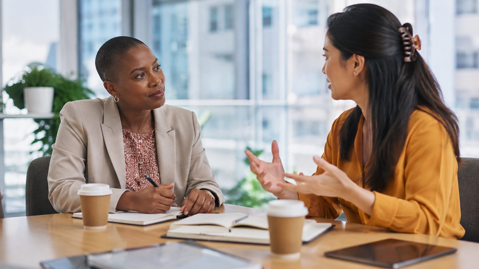 Professional business scene showing a leader having an engaged one-on-one conversation with a team member in a modern office setting.