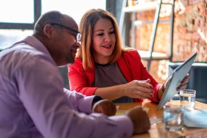 Manager in discussion with team member pionting to tablet while sitting at a table.